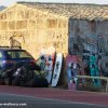 Thumb Picture: A car parked on the side of a road next to kiteboards leaning on a wall .