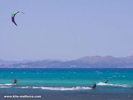 Three people kiteboarding over a body of water by good wind conditions .