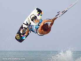 A man flying through the air while riding a kiteboard.