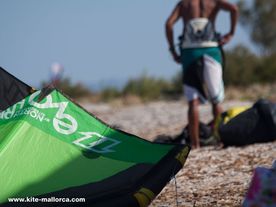A man standing on top of a sandy beach, waiting for the right wind for kitesurfing.