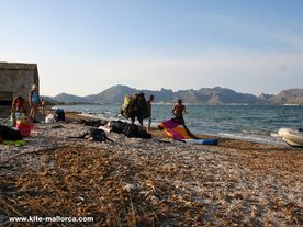 A group of people sitting on top of a sandy beach .