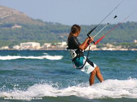 A man riding a wave on top of a kiteboard .