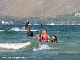 Gerhard with students on bodydrag A group of people riding on top of a wave in the water behind a kite.