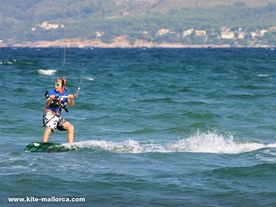 A child riding a wave on top of a kiteboard and hanging on a kite.