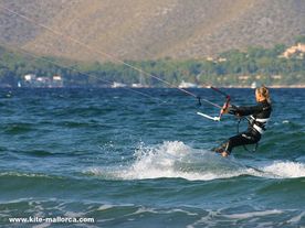 Eli in the waves a girl surfing a wave on top of a kiteboard.